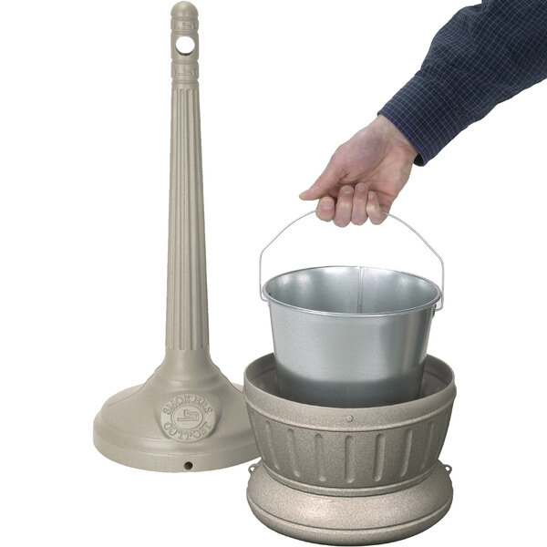 A hand holding a metal pail with a lid.