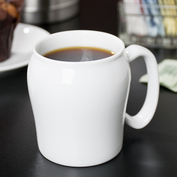 A white Cambro contoured mug filled with brown liquid on a table.