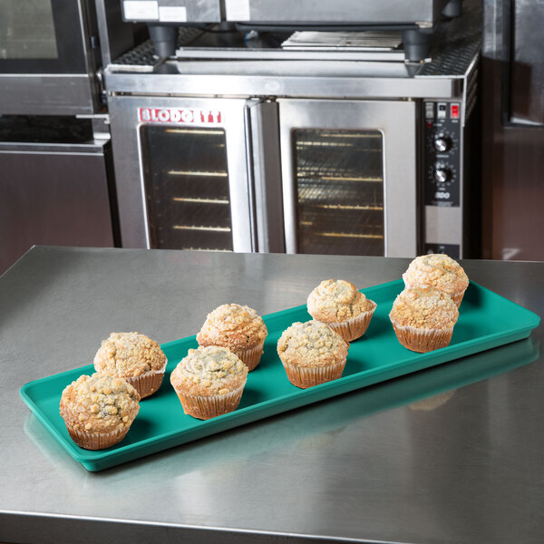 A MFG Tray mint green fiberglass display tray with muffins on it.