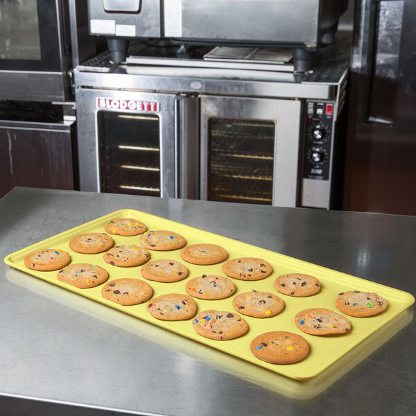 A yellow MFG Fiberglass Supreme Display Tray holding cookies on a counter.