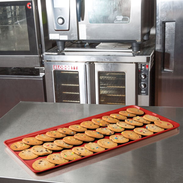 A red MFG Fiberglass Supreme Display Tray holding cookies on a counter.