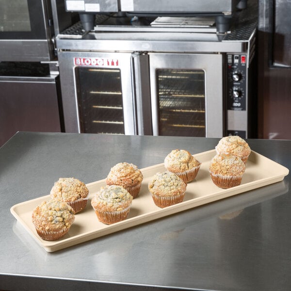 A beige MFG Tray supreme display tray holding muffins on a counter.