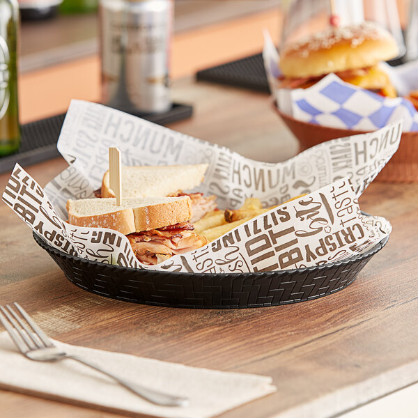 A black plastic fast food basket on a table with a sandwich and a drink.