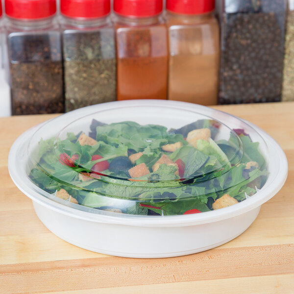 A salad in a 48 oz. white round microwavable container with a lid.