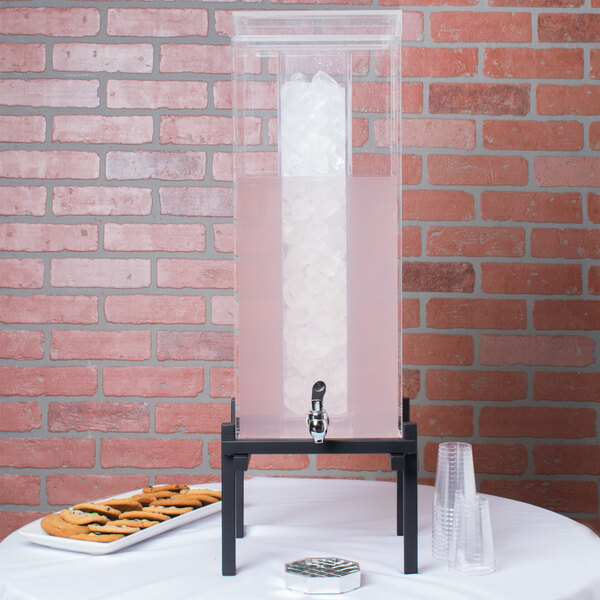 A Cal-Mil 5 gallon acrylic beverage dispenser chamber with ice in it and a pink drink.