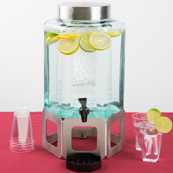 A Cal-Mil stainless steel beverage dispenser with lemons and a glass.