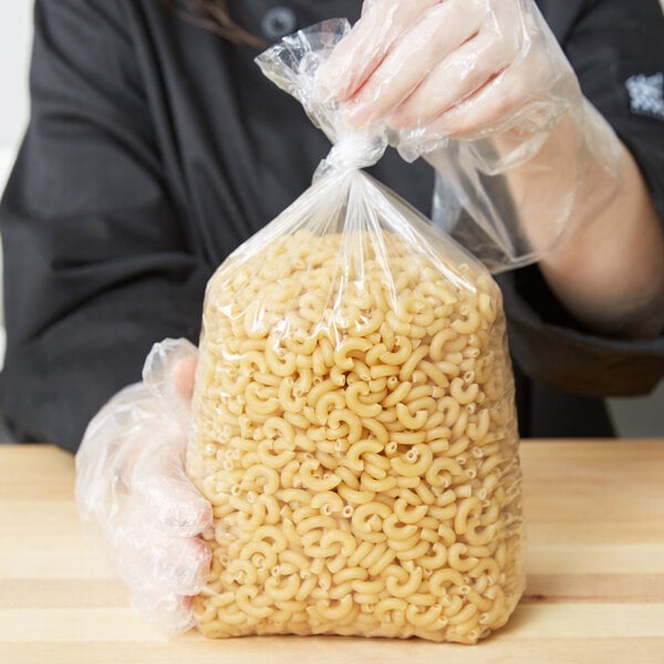 A person in a LK Packaging plastic bag holding a bag of pasta.