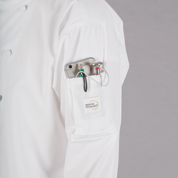 A person wearing a Mercer Culinary white chef jacket with a phone in the pocket.