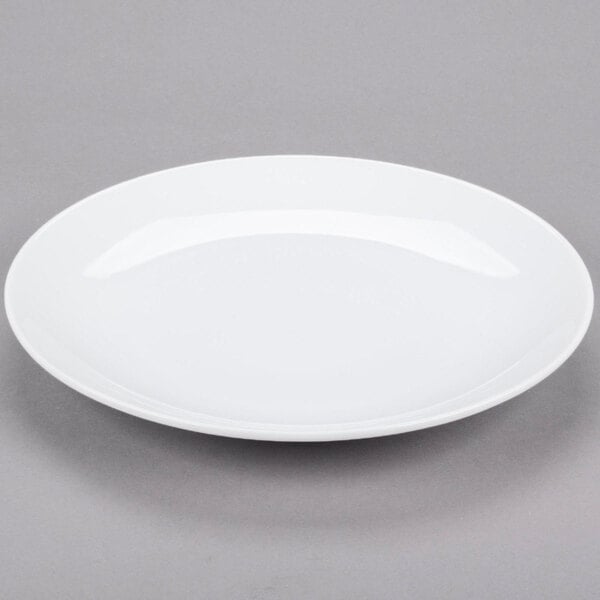 A Libbey Aluma White Porcelain Coupe Plate on a gray surface.