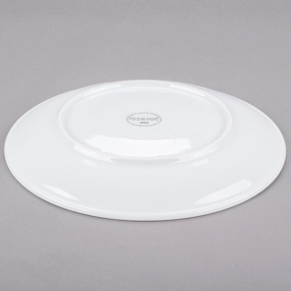 A Libbey Aluma White porcelain coupe plate with a circular rim on a gray surface.