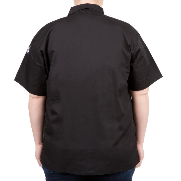 A person wearing a black Chef Revival short sleeve cook shirt.