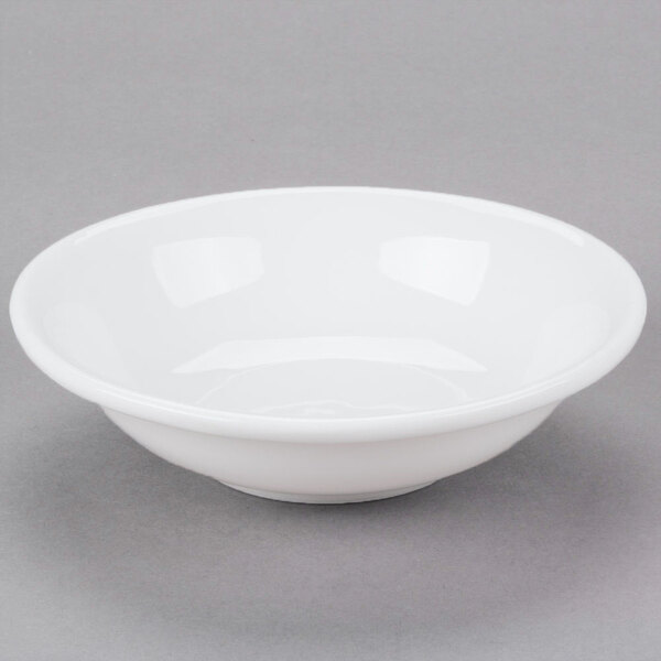 A Libbey white porcelain fruit bowl with a small rim on a gray surface.