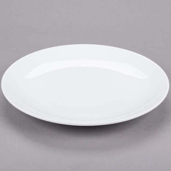 A Libbey Aluma White porcelain coupe plate with a rim on a gray surface.