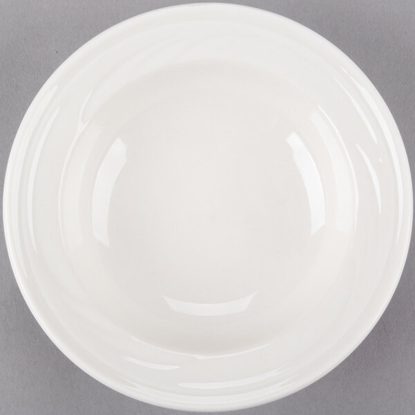 A Libbey ivory porcelain fruit bowl with a rim on a gray surface.