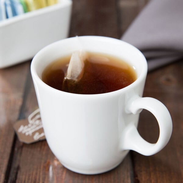 A close-up of a white Libbey tall tea cup with a tea bag in it.