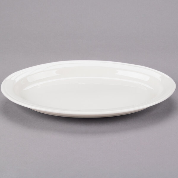 An ivory Libbey oval medium rim porcelain platter on a gray surface.