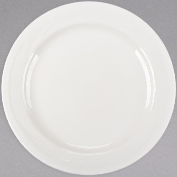 A close up of a Libbey ivory porcelain plate with a curved edge on a white surface.