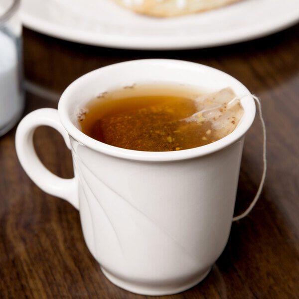 A Libbey porcelain tall tea cup filled with tea on a table.