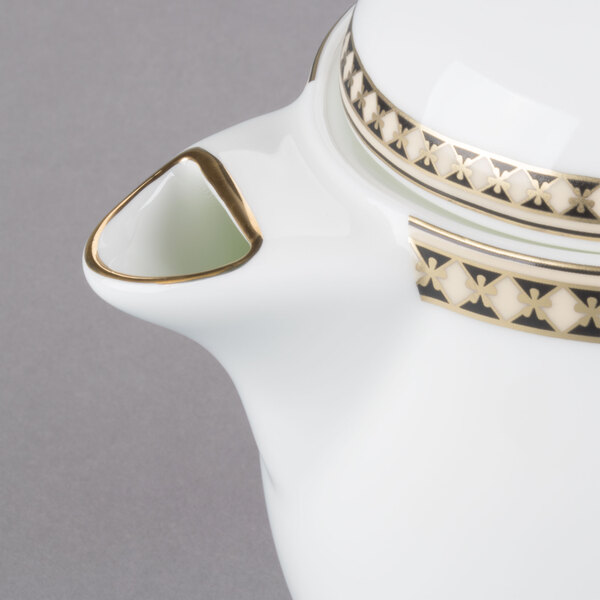 A white Syracuse China teapot with gold trim and a handle.