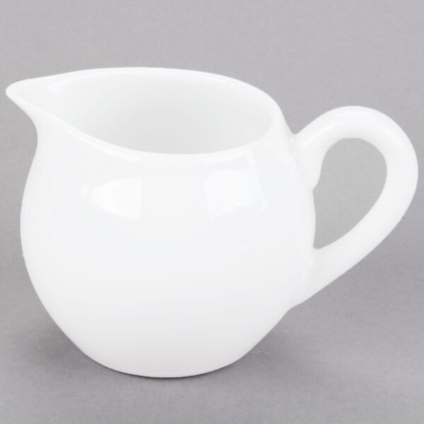 A Libbey Aluma White porcelain creamer with a handle.