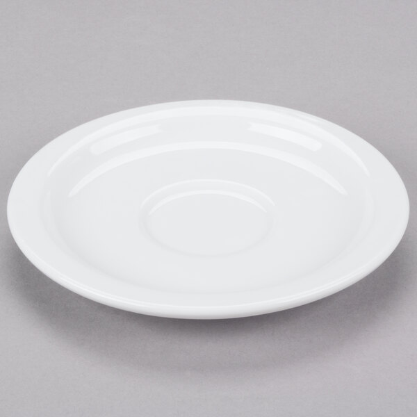 A Libbey white porcelain saucer with a circular edge on a gray surface.
