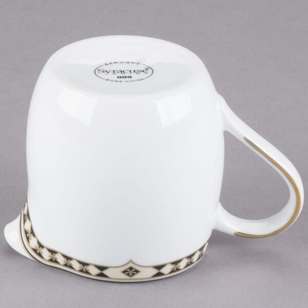 A white Syracuse China creamer with a black and gold Baroque design.