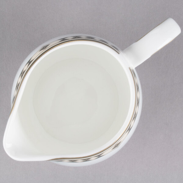 A white Syracuse China creamer pitcher with a black rim and handle.