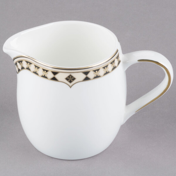 A white and gold Syracuse China Baroque creamer with a design on the handle.