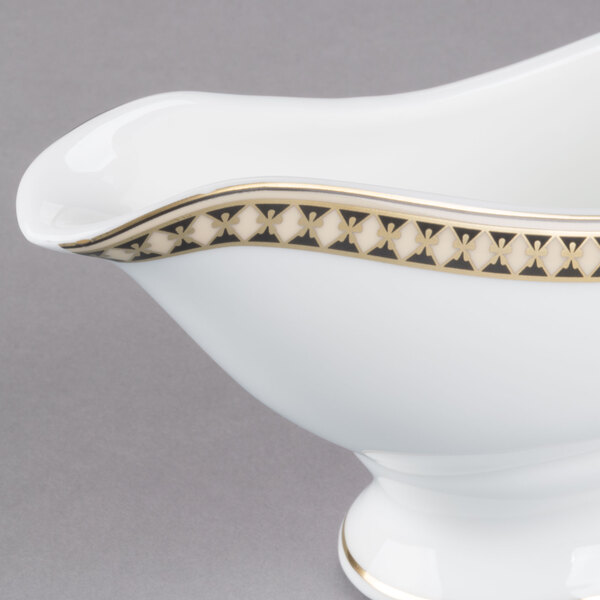 A white bone china gravy boat with a gold trim.