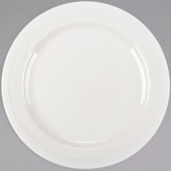 A close up of a Libbey ivory porcelain plate with a curved rim on a white surface.