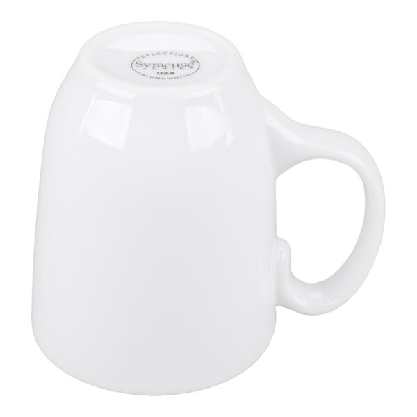 A white ceramic mug is shown upside down with a handle visible on the right side.