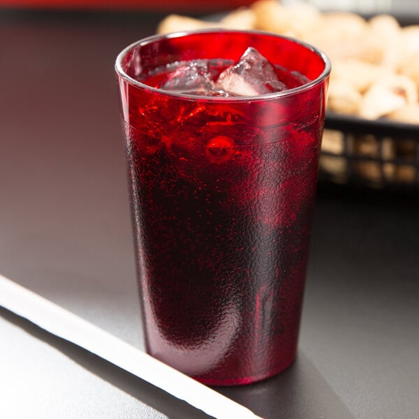 a glass of red liquid with ice and a straw