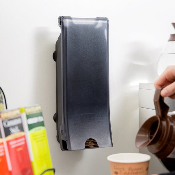 A person pouring coffee into a San Jamar coffee sleeve dispenser.