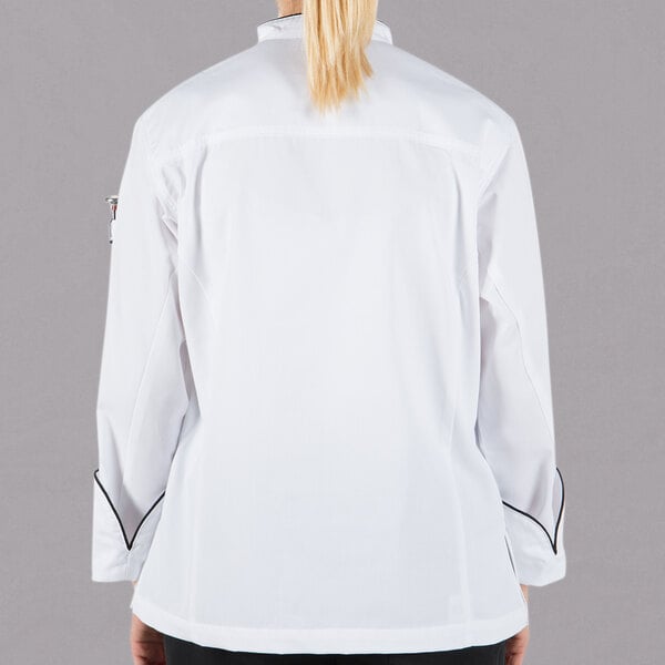A woman wearing a Mercer Culinary white chef jacket with black piping.