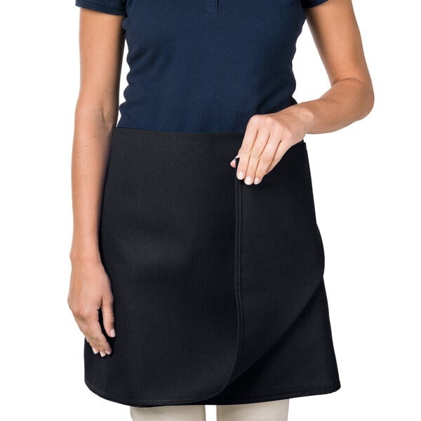 A woman wearing an Intedge black poly-cotton waist apron.