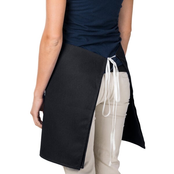 A woman wearing a black Intedge waist apron with white ties.