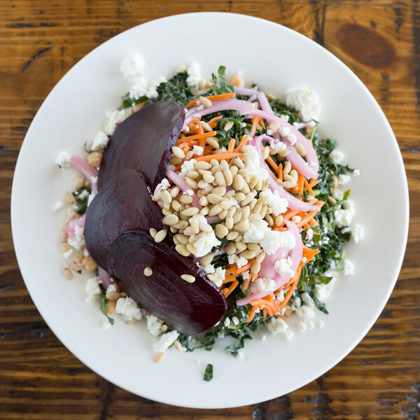 A 10 Strawberry Street Bistro bright white porcelain dinner plate with a salad of beets, carrots, nuts, and feta.