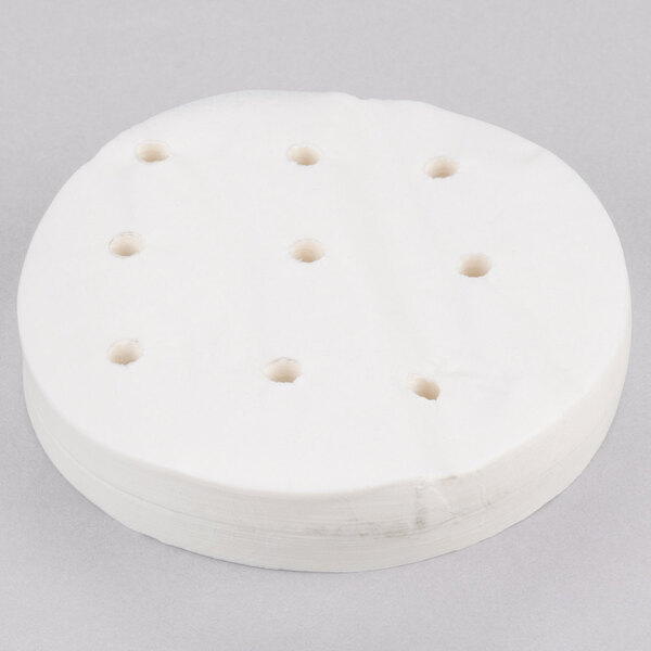 A stack of white circular patty paper with holes in it.