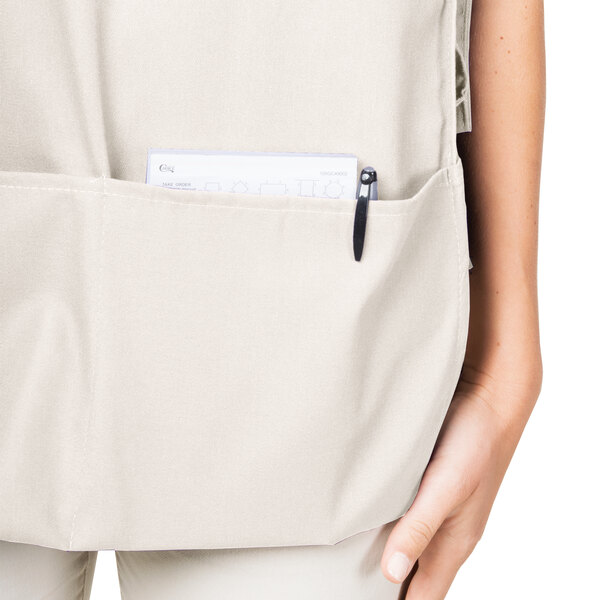 A woman wearing an ivory Intedge cobbler apron with pockets.