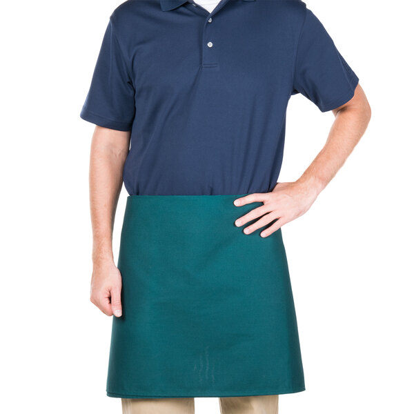 A man wearing a green Intedge waist apron over a blue shirt.