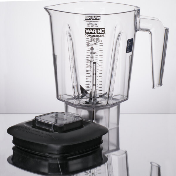 A clear Waring blender jar with a black lid on a table.