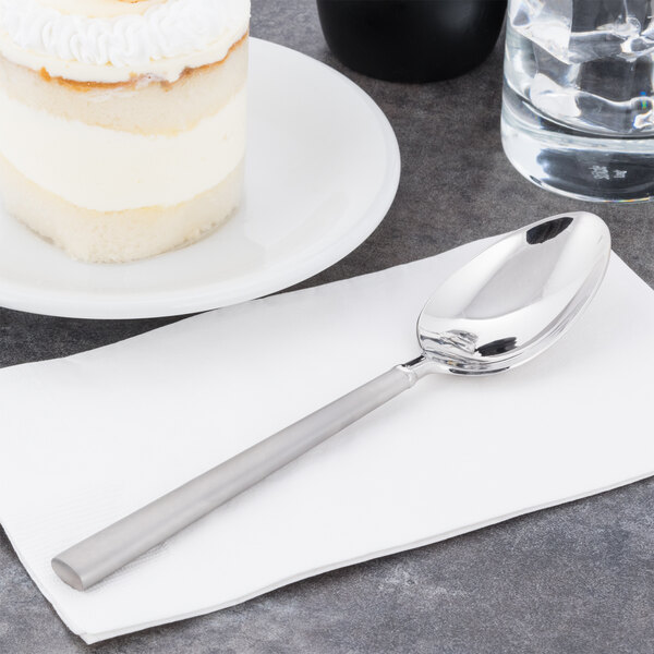 A Libbey stainless steel dessert spoon on a napkin next to a cake.