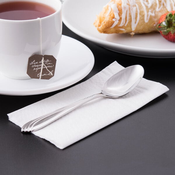 A cup of tea with a Libbey stainless steel teaspoon on a napkin.