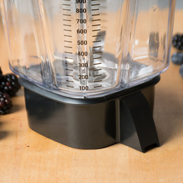 A Waring blender jar pad with blackberries on a wood surface.
