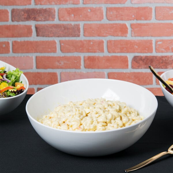 A white Tablecraft Sierra melamine bowl filled with macaroni salad on a table with bowls of food.