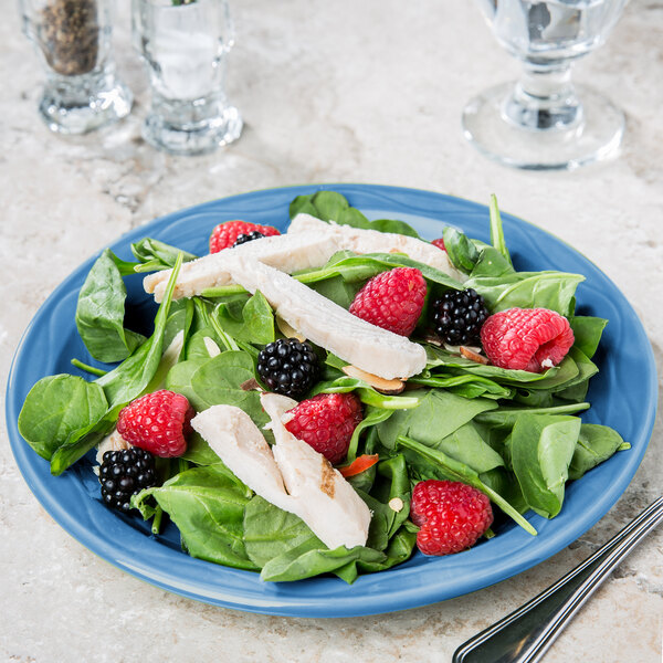 A blue Libbey Cantina porcelain plate with a salad of spinach, berries, and chicken.