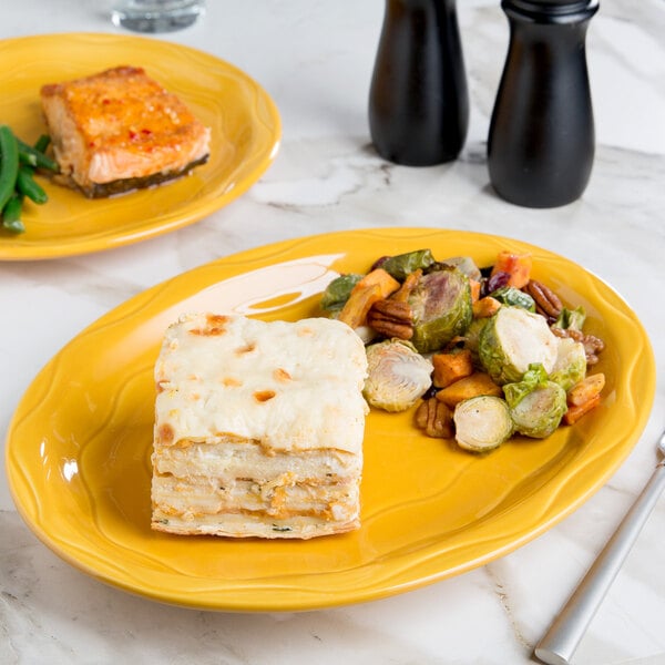 A Libbey saffron oval porcelain platter with food on a table.