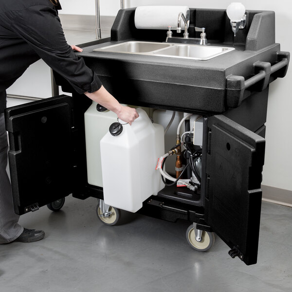 A woman using a Cambro CamKiosk portable self-contained hand sink.