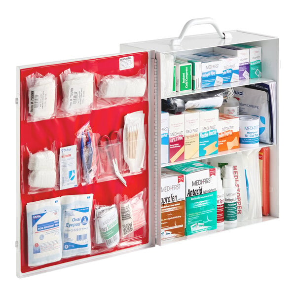 An open first aid kit cabinet with multiple shelves and compartments containing various medical supplies such as bandages, gauze, medications, ointments, and first aid tools.