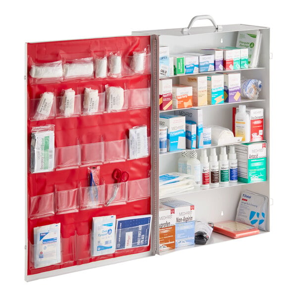 An open metal cabinet containing a variety of first aid supplies organized in clear pockets and on shelves.